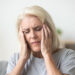 Upset middle aged older woman massaging temples touching aching head feeling strong headache or migraine concept, sad tired stressed elderly senior mature woman suffering from pain or dizziness