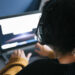 rear view of a entrepreneur woman with headphones working on laptop at home, technology and teleworking concept, selective focus
