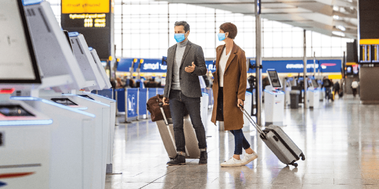 Turistas transitan por aeropuerto con equipaje cumpliendo con las medidas preventivas