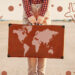 Mujer turística que sostiene una maleta con mapa al aire libre. Tipos de transporte alrededor de la oferta turística