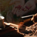 Montaje de taza de café en tabla de madera; bolsa con granos de café, café molido; manos sostienen granos de café recién cosechados