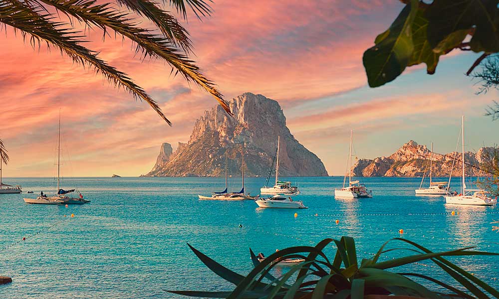 Pequeños yates navegando en las aguas cristalinas de Ibiza